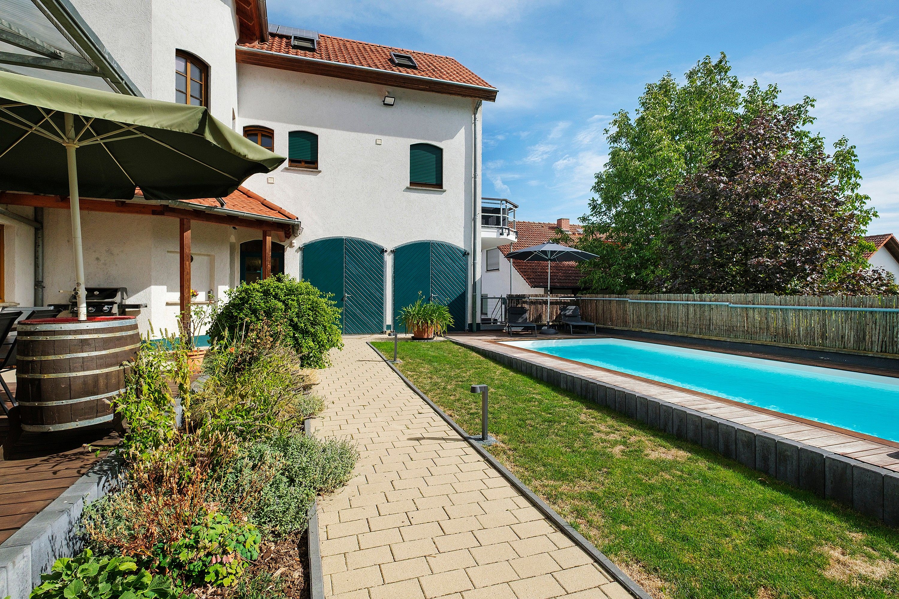 Ein Wohnhaus mit Swimmingpool, überdachter Terrasse und Garten.