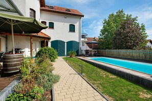 A residential property with a swimming pool, a covered patio, and a garden area.
