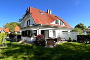 Ein zweistöckiges Haus mit rotem Dach, weißem Anstrich und einem gepflegten Rasen.