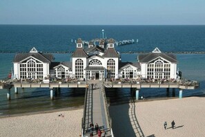 Een gebouw aan het water met veel ramen en een steiger die het water in reikt.