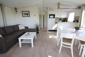 Ein modernes Wohnzimmer mit Sofa, Couchtisch und Essbereich mit Stühlen.