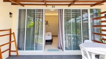 Une chambre comprenant un lit, une table et une porte-fenêtre coulissante donnant sur un espace extérieur avec une table et des chaises.