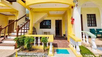 A yellow building with a staircase, a balcony, and a door marked T2.