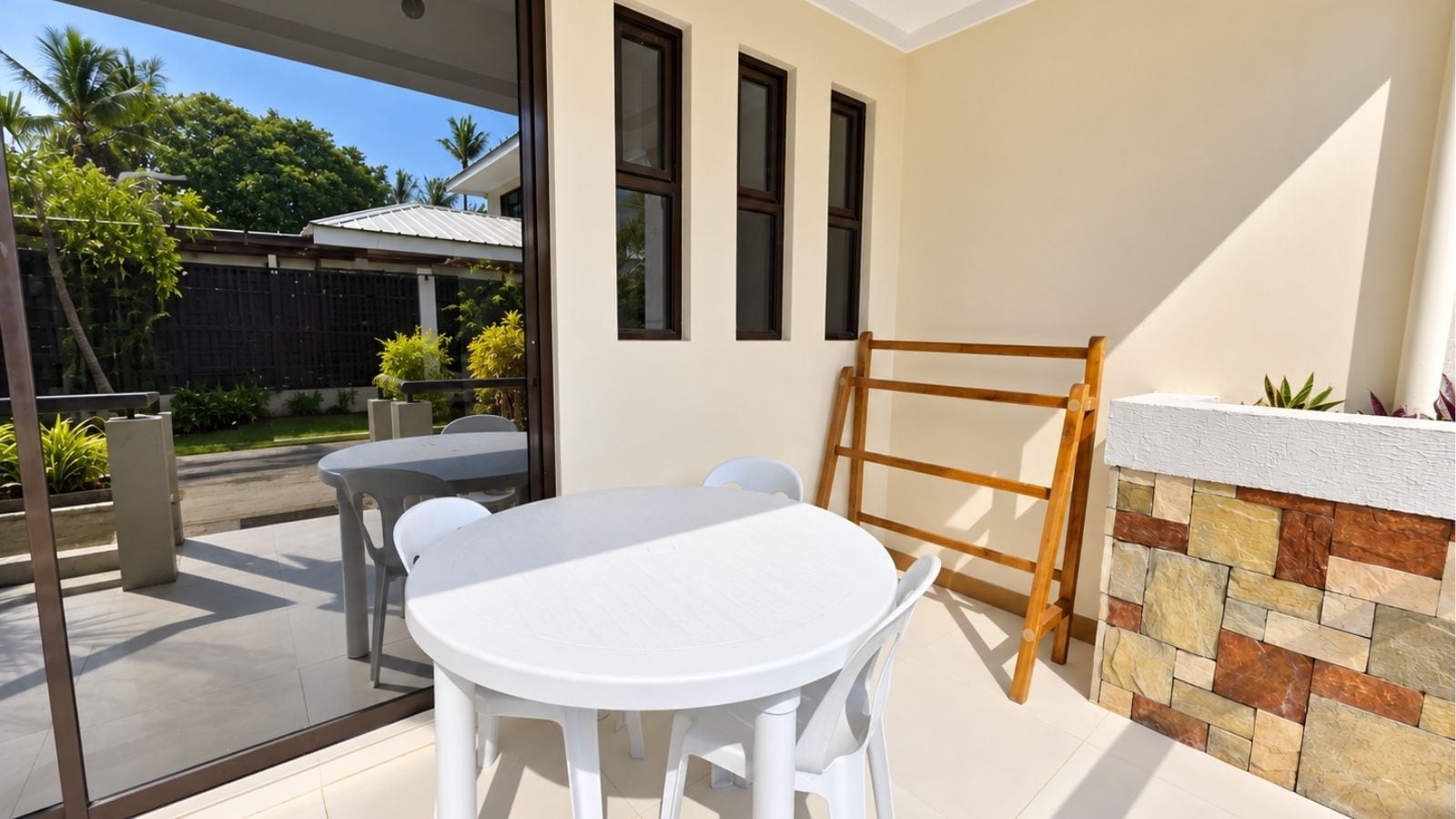 Un patio con una mesa redonda y sillas, una escalera de madera y un muro de piedra.