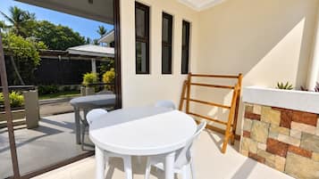 Un patio con una mesa redonda y sillas, una escalera de madera y un muro de piedra.