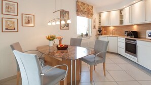 Une cuisine moderne avec des meubles blancs, un îlot central doté de sièges et une table à manger avec des chaises.