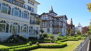 Un bâtiment de style européen traditionnel, doté d’un jardin bien entretenu et surplombant un ciel dégagé.