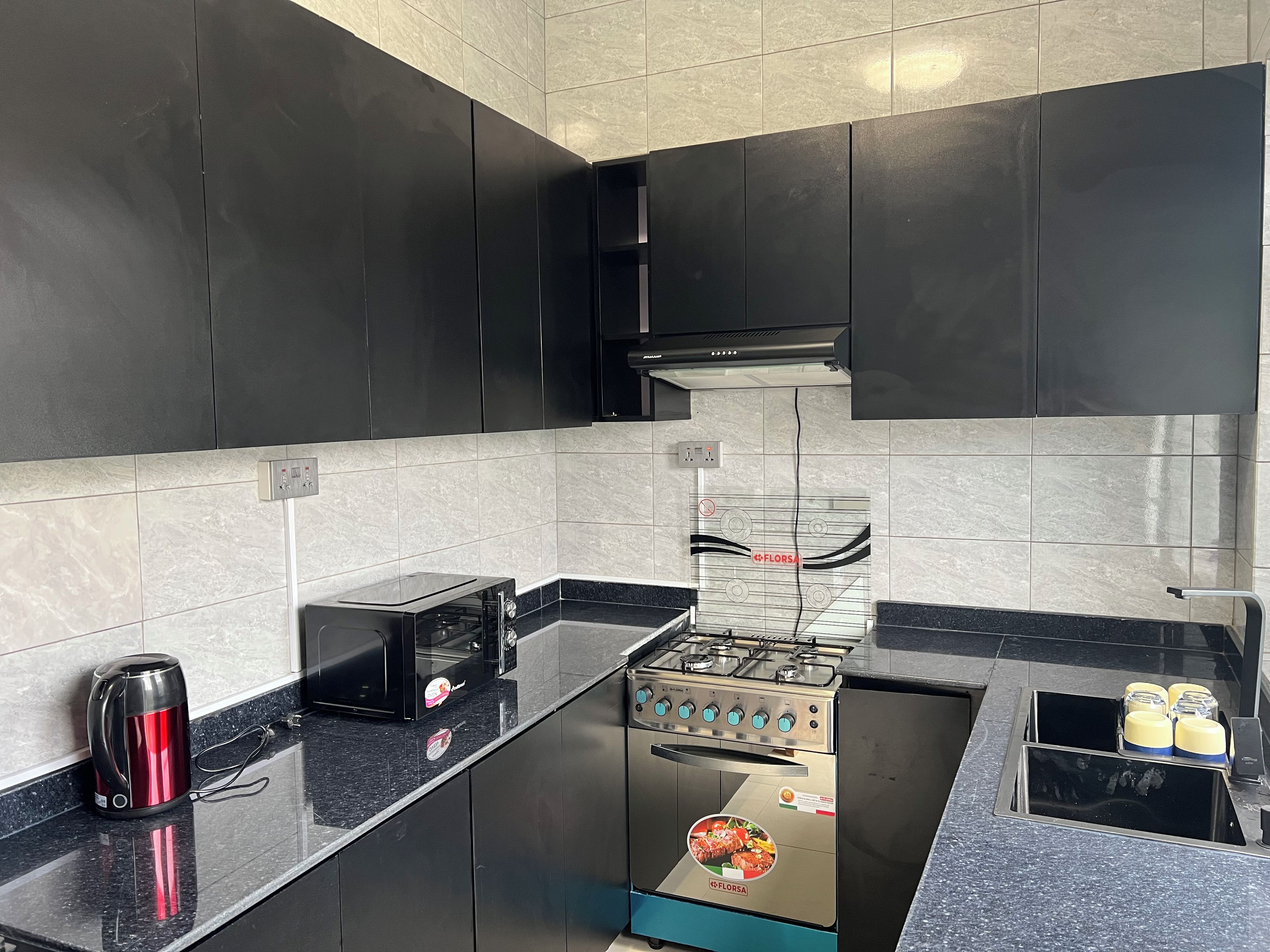 Una cocina moderna con gabinetes negros, una estufa de acero inoxidable y una encimera negra.