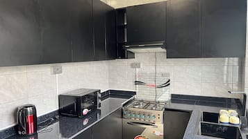 Una cocina moderna con gabinetes negros, una estufa de acero inoxidable y una encimera negra.