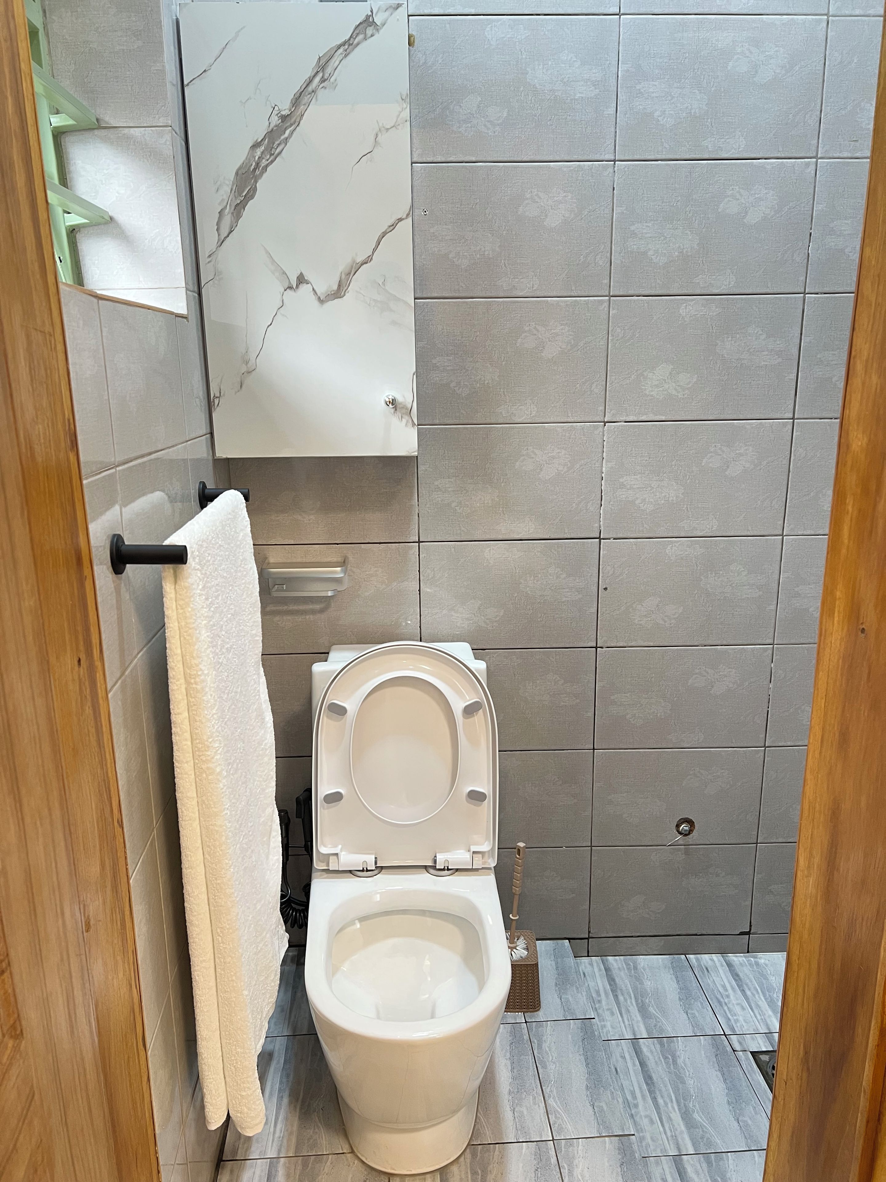 A bathroom with a toilet, a towel rack, and a mirror.