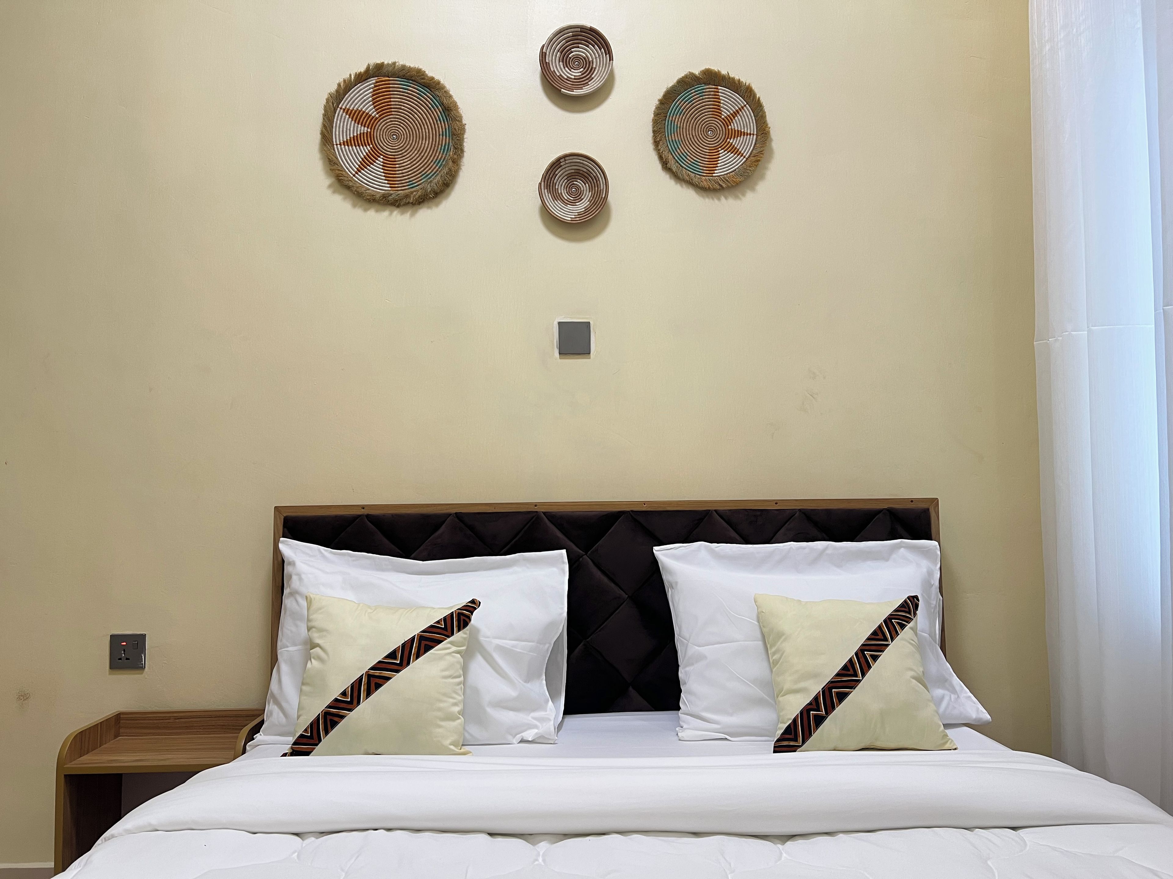 Ein Hotelzimmer mit einem Bett, zwei Kissen, einem Kopfteil und drei Wanddekorationen.