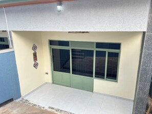A room with a green door, tiled floor, and a wall-mounted light fixture.