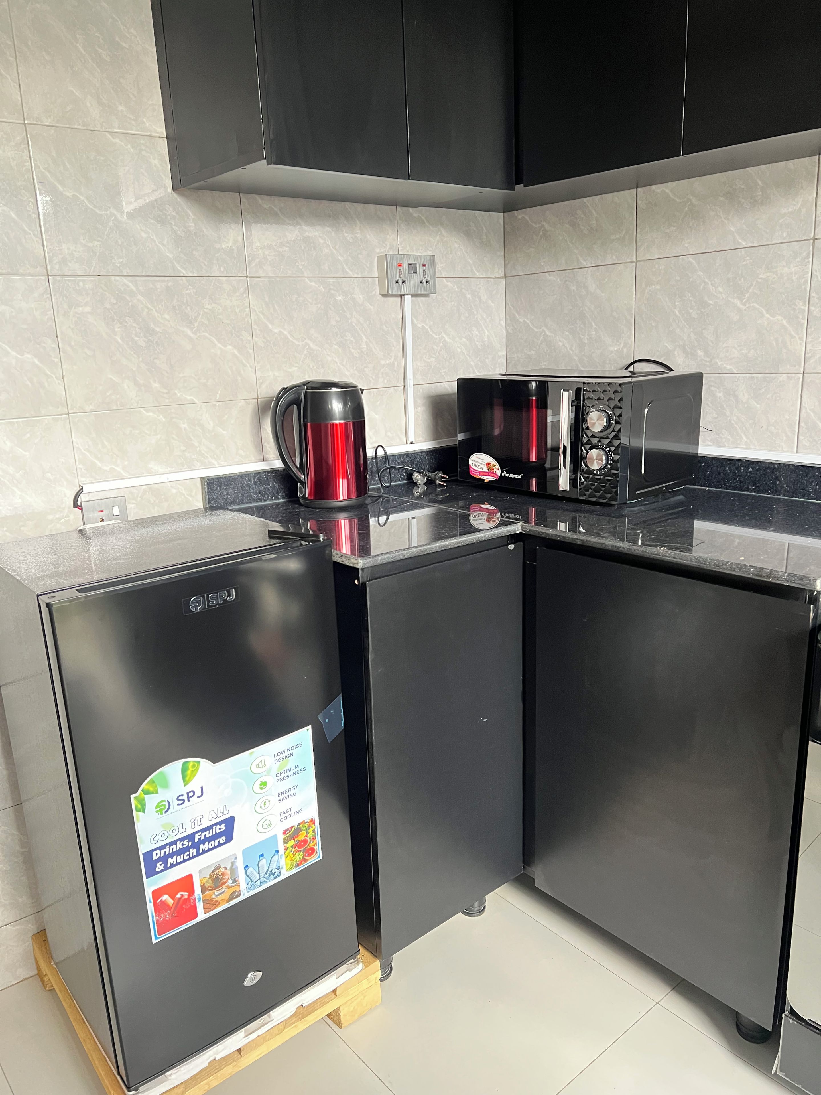 A compact kitchen with a refrigerator, a coffee maker, and a microwave.