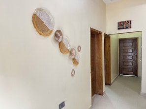 A hallway with a series of wall-mounted circular wall decorations, a wooden door, and a small painting on the wall.