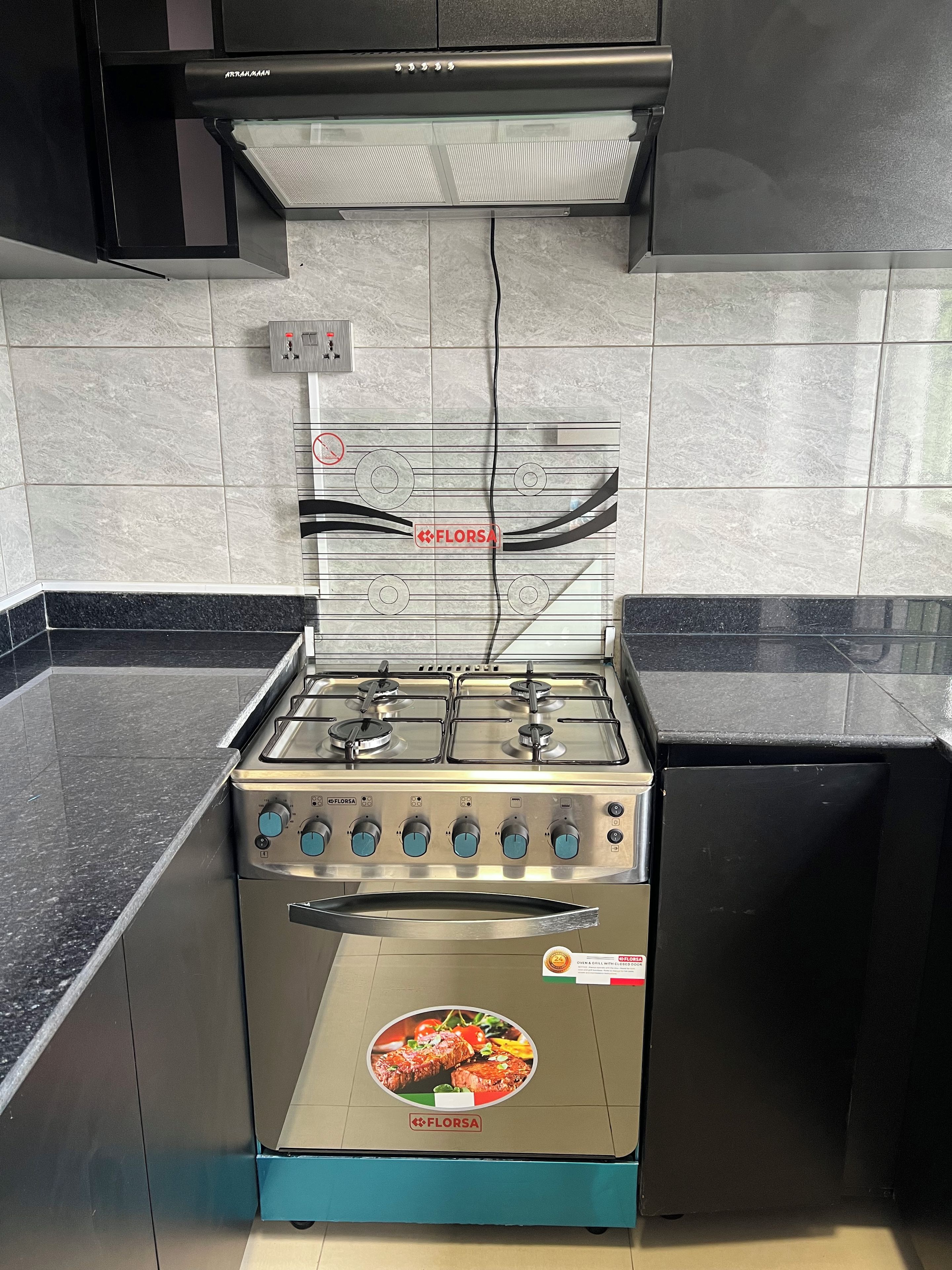 Une cuisine équipée d’une cuisinière à gaz, d’une hotte aspirante et d’un pare-feu en carreaux.