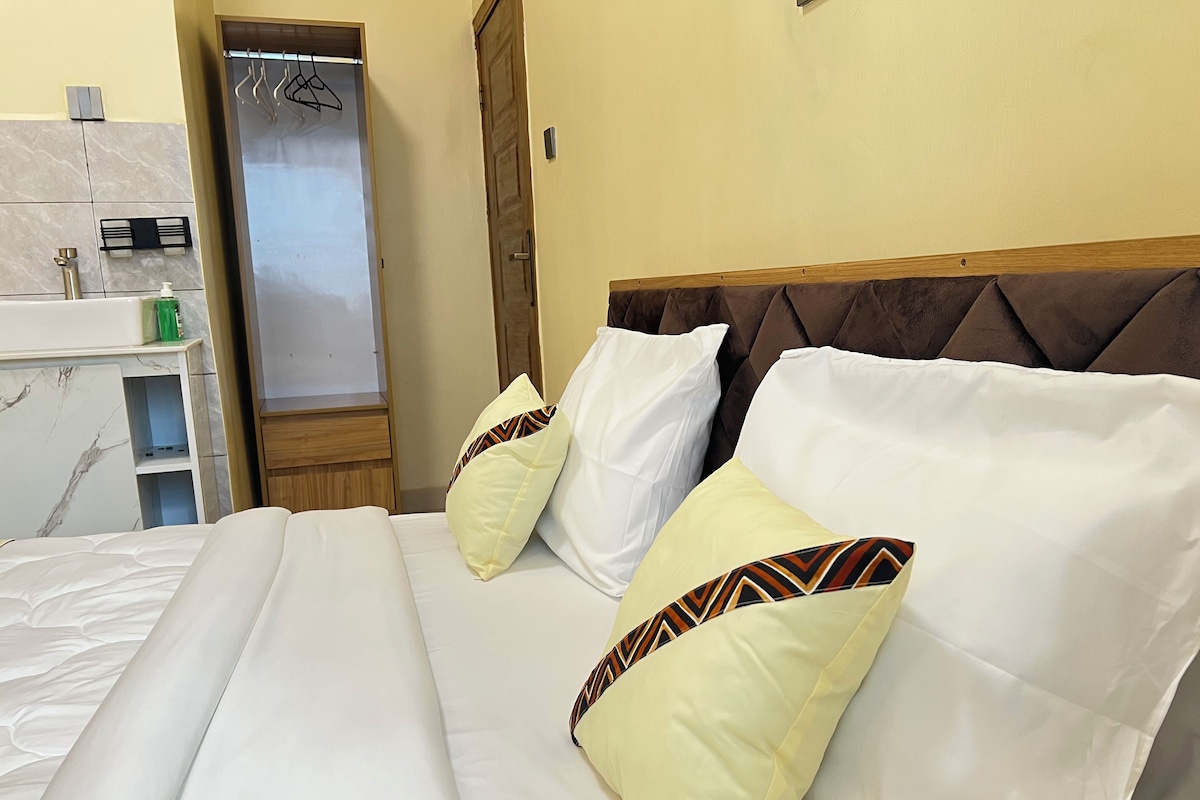 A hotel room with a bed, a wardrobe, a mirror, and a sink.
