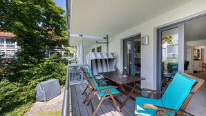 Ein Balkon mit Tisch und Stühlen, einem Grill und einem überdachten Bereich.