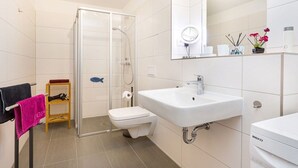 Une salle de bain moderne avec une douche à parois de verre, un lavabo blanc et des toilettes.