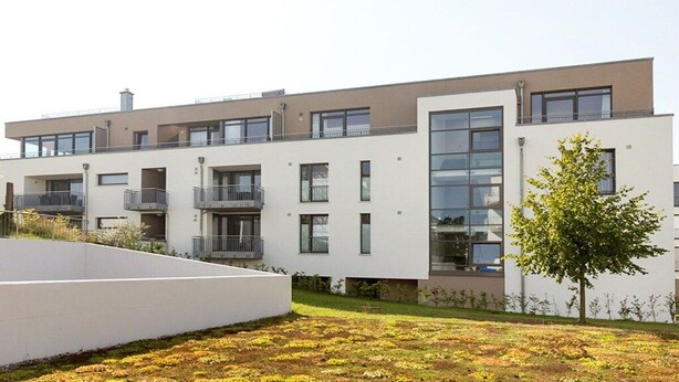 Un immeuble résidentiel moderne à plusieurs étages, doté de balcons et de grandes fenêtres.