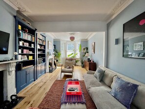 A living room with a fireplace, a sofa, a coffee table, and a bookshelf. - Spacious 1BDR Flat with Garden in Brockley (Greater London)