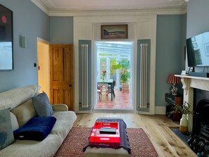 A living room with a sofa, a coffee table, a television, and a view of the outside patio. - Spacious 1BDR Flat with Garden in Brockley (Greater London)