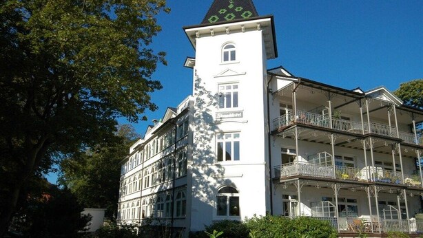 Ein mehrstöckiges Gebäude mit einem markanten Turm, der eine Uhr zeigt.