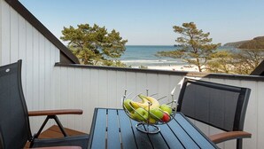 Ein Balkon mit Tisch, Stühlen und einer Obstschale.
