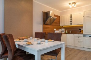 A modern kitchen with white cabinets, a stainless steel range hood, and a breakfast setup on a white table. - 3 - in the Granitz house (Binz)