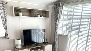 Una sala de estar moderna con un televisor de pantalla plana, un sofá gris y una mesa de centro.