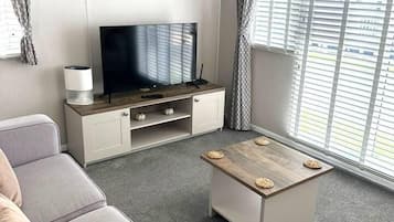 Una sala de estar moderna con un televisor de pantalla plana, un sofá gris y una mesa de centro.