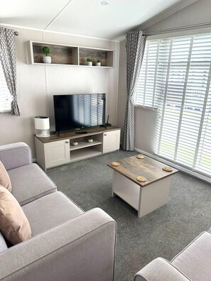 Una sala de estar moderna con un televisor de pantalla plana, un sofá gris y una mesa de centro.