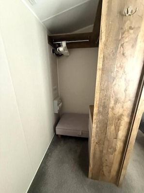 A small room with a bed, a wooden door, and a light fixture on the ceiling.