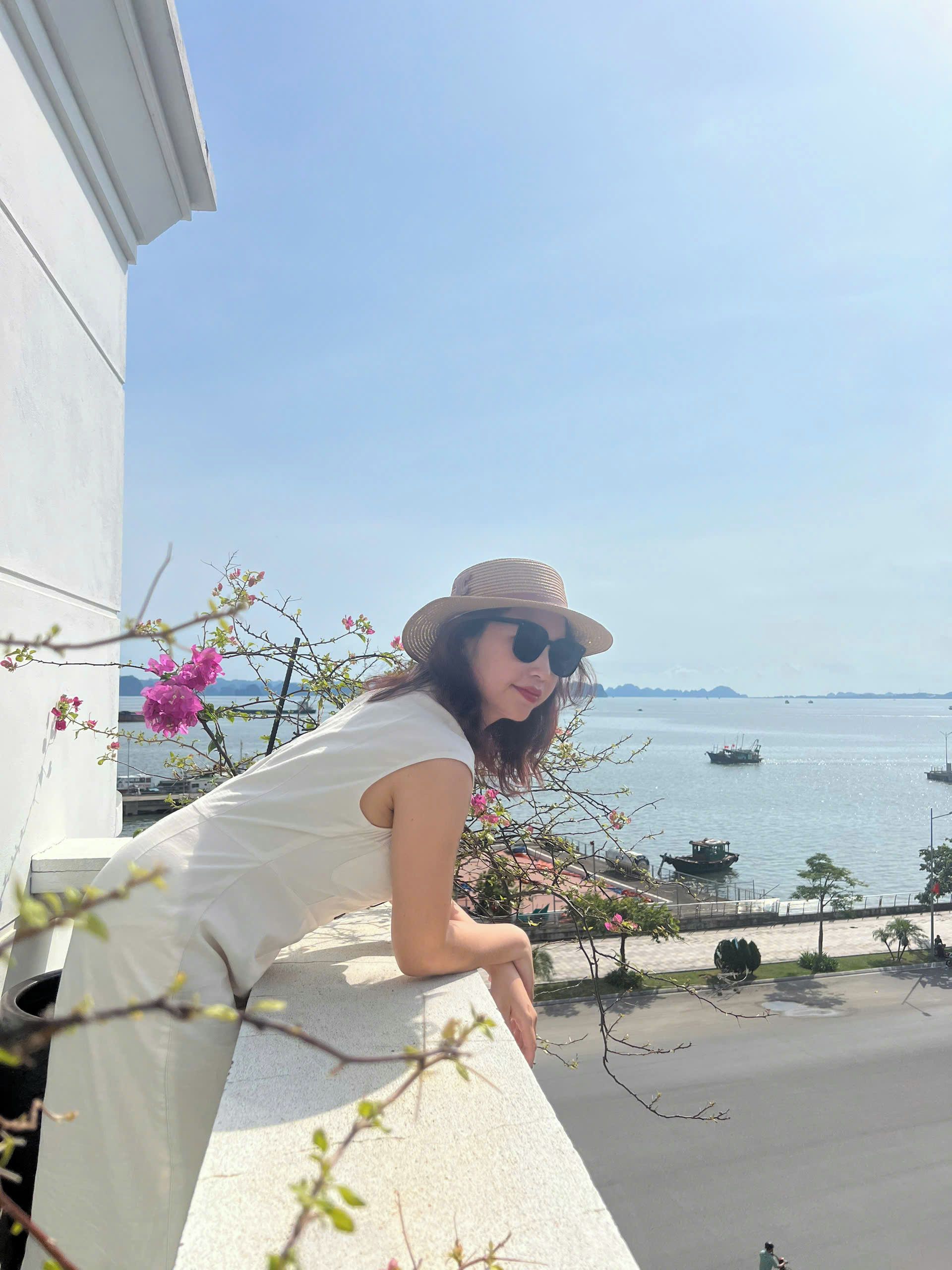 A person leaning on a balcony with a view of the sea and boats.