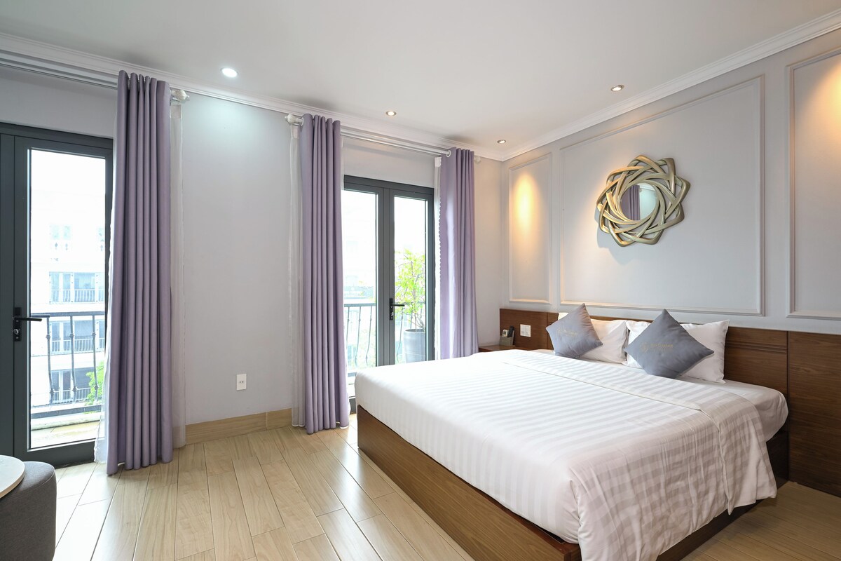 Habitación de hotel con una cama grande, un espejo redondo y vistas al exterior.