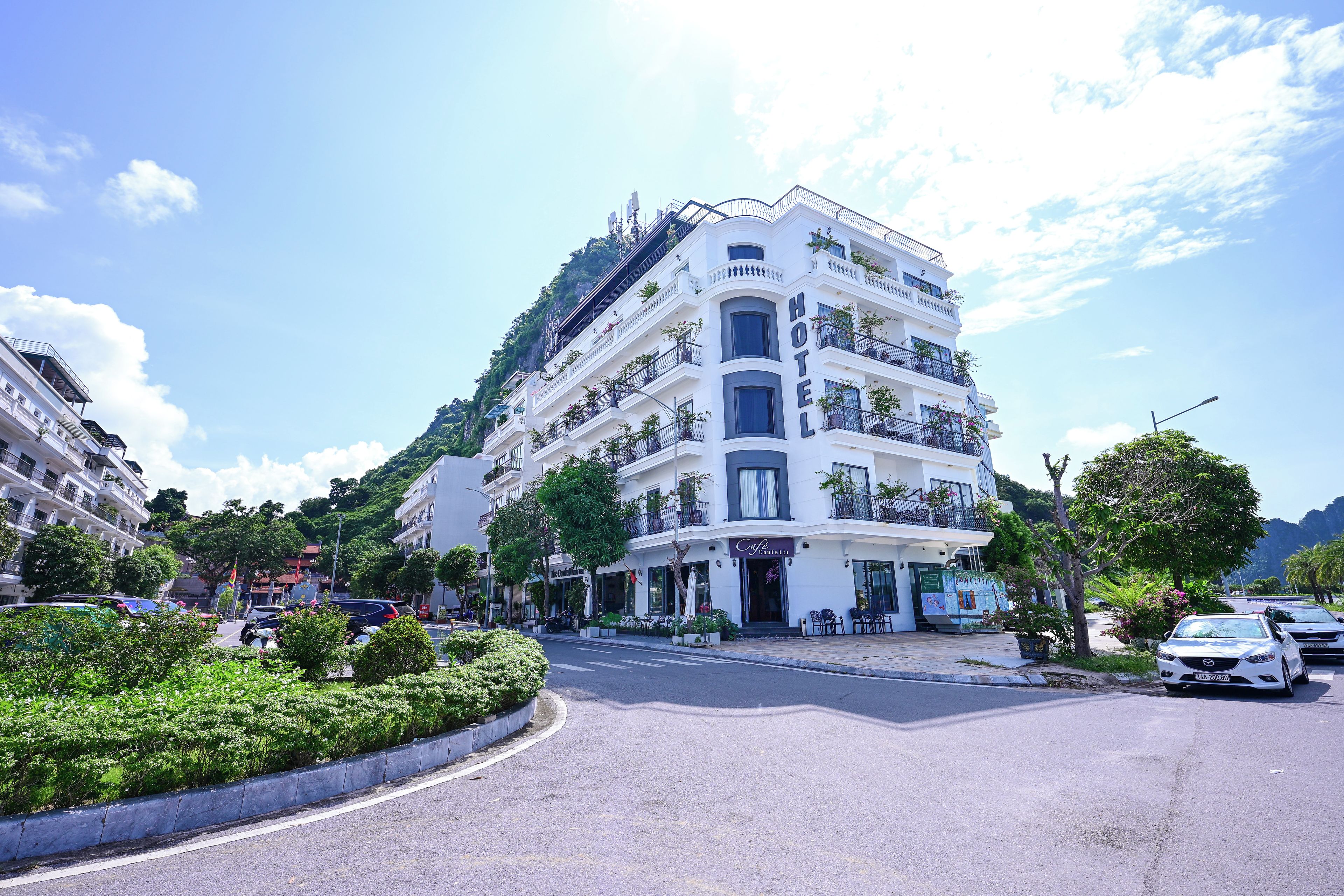 Un hôtel à plusieurs étages doté de balcons, d’un café et offrant une vue sur la verdure environnante.