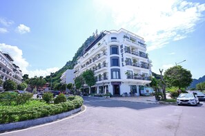 Un hotel de diverses plantes amb balcons, una cafeteria i vistes a la vegetació circumdant.