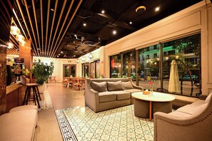A modern interior with a sofa, chairs, a dining area, and large windows. - The Confetti Hotel Ha Long (Hong Gai)