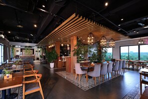 Un interior moderno con listones de techo de madera, un mostrador de recepción y zonas de estar con mesas y sillas.