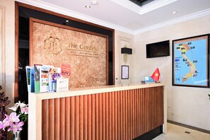 Una recepción con detalles de madera, un letrero que dice 'The Confetti Hotel' y un mapa de Vietnam.