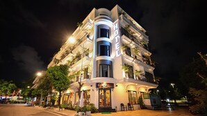 A multi-story hotel with a prominent 'HOTEL' sign, outdoor seating area, and balconies with plants. - The Confetti Hotel Ha Long (Hong Gai)