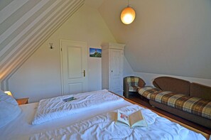 A bedroom with two beds, a wardrobe, a chair, and a sofa. - Vacation home with a fireplace and sauna, about 300 meters from the sandy beach; pets welcome (Glowe)