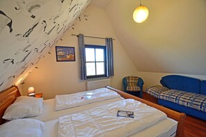 A bedroom with two beds, a window, a chair, and a sofa. - Vacation home with a fireplace and sauna, about 300 meters from the sandy beach; pets welcome (Glowe)