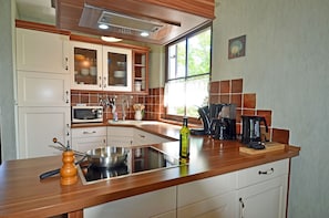 A kitchen with a wooden countertop, a sink, a microwave, and a coffee maker. - Vacation home with a fireplace and sauna, about 300 meters from the sandy beach; pets welcome (Glowe)