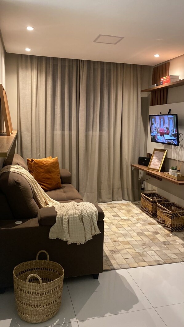 Una sala de estar con un sofá, un televisor y una estantería de pared.