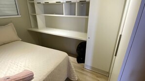 Quarto com cama, roupeiro embutido e janela.