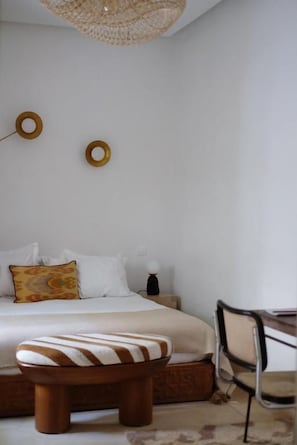 A bedroom with a bed, a nightstand, a chair, and a hanging light fixture. - Riad L'Atelier (Marrakech)