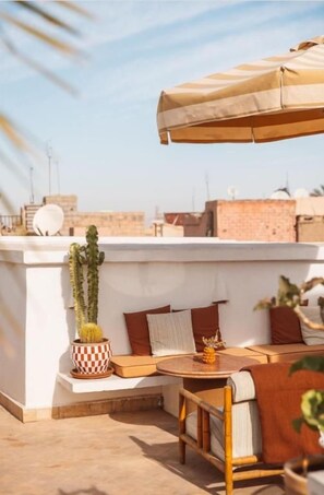 A rooftop terrace with a seating area, a table, and a potted plant. - Riad L'Atelier (Marrakech)