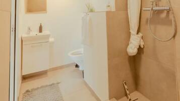 A bathroom with a shower, a toilet, and a sink.