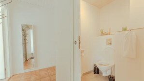 A bathroom with a toilet, bidet, and a small shelf with toiletries. - Bøkjarabrekka (Tórshavn)