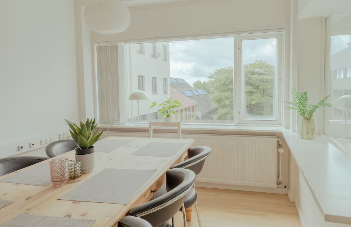 A modern dining area with a wooden table, chairs, and a view of the outside.